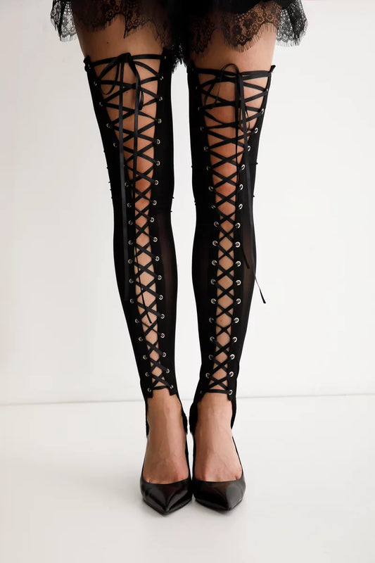 Black thigh-high stockings, front view of eyelet lace-up detailing running down to an open heel cut-out