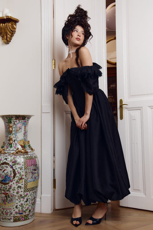 Black corset dress, three-quarter view of the fitted bodice meeting the balloon-hem skirt