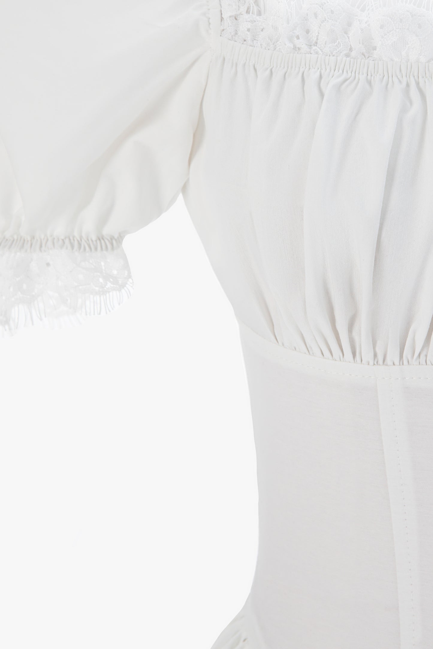 Close-up of a white off-the-shoulder  cotton dress with gathered elastic details.