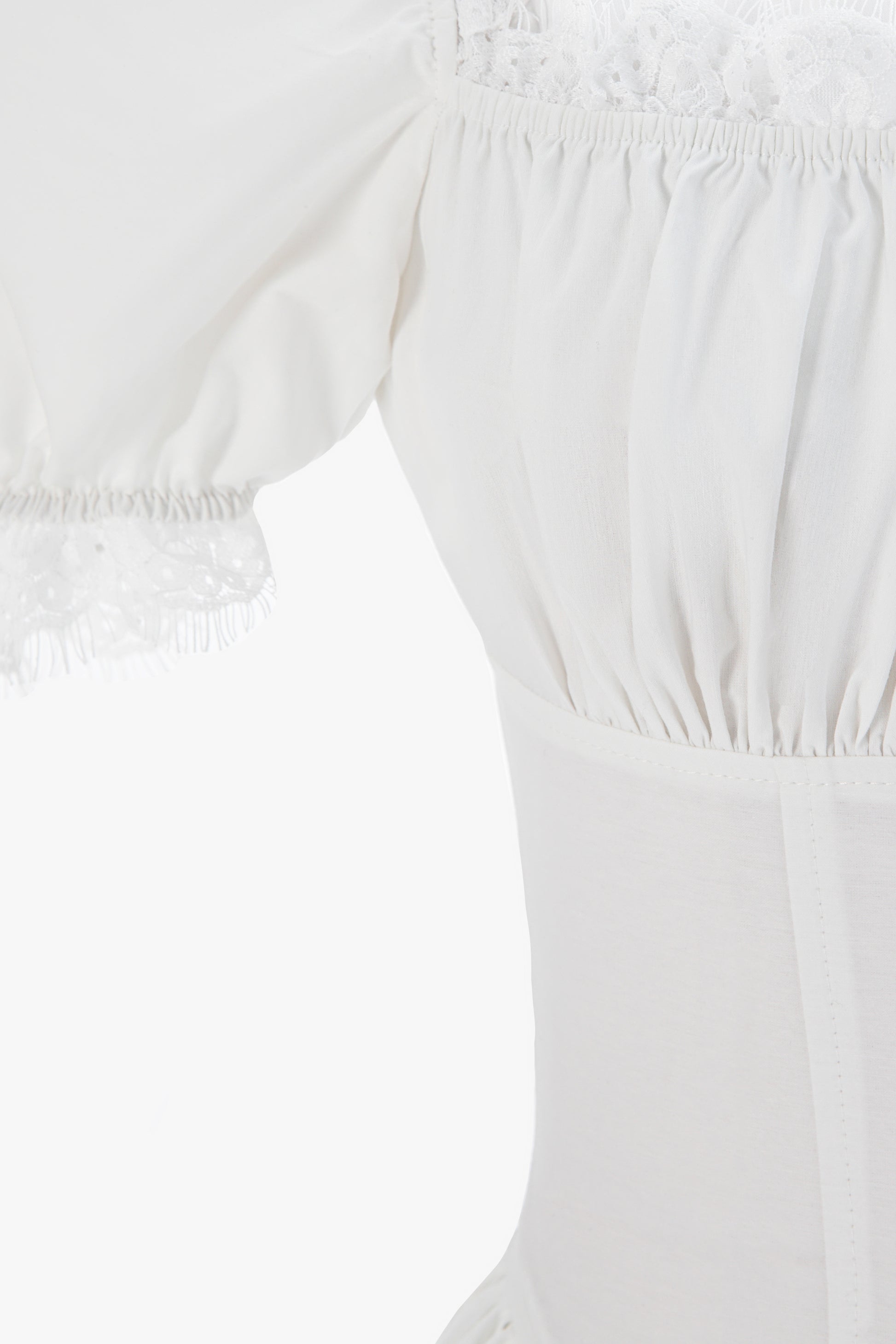 Close-up of a white off-the-shoulder  cotton dress with gathered elastic details.