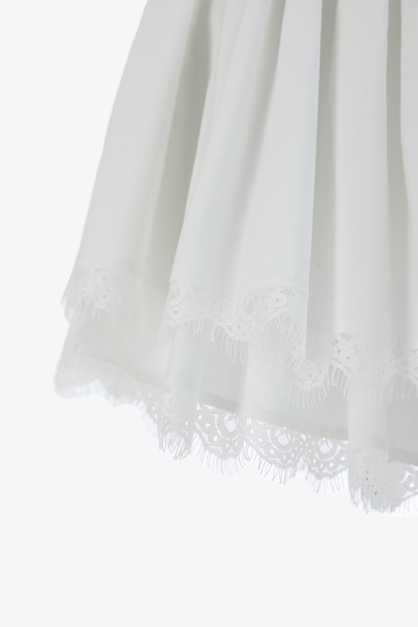 Close-up of a white sheer tulle skirt of the dress with delicate lace trim along the hem.